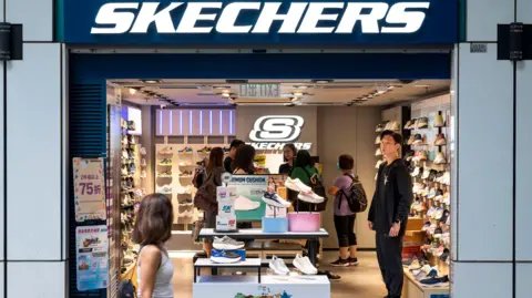 Getty Images Pedestrian walking past a store of the American lifestyle and performance footwear brand Skechers.