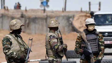 AFP via Getty Images Three unidentified soldiers from Niger wearing camouflages and helmets, holding guns